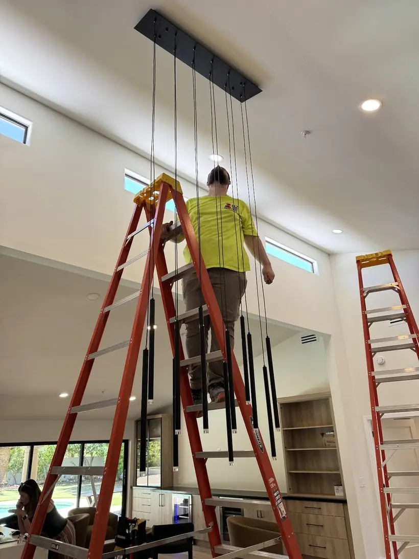 Electrician installing a light fixture in a home